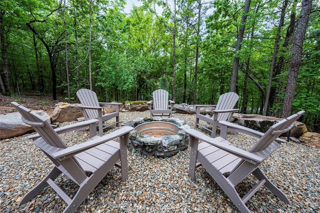 view of patio / terrace featuring an outdoor fire pit and a wooded view