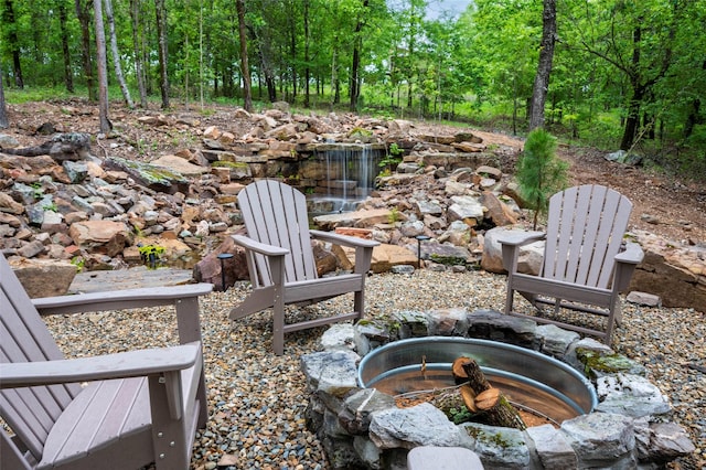 view of patio / terrace featuring an outdoor fire pit and a wooded view