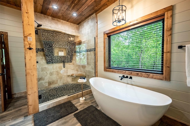 full bathroom with wood walls, wood finished floors, wood ceiling, a freestanding bath, and a shower stall