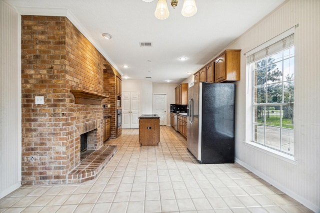 kitchen featuring plenty of natural light, a kitchen island, ornamental molding, and stainless steel refrigerator with ice dispenser