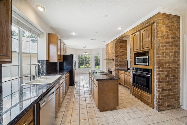 kitchen featuring sink, a center island, hanging light fixtures, light tile patterned flooring, and appliances with stainless steel finishes