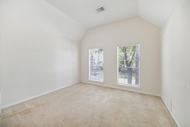 carpeted spare room featuring vaulted ceiling