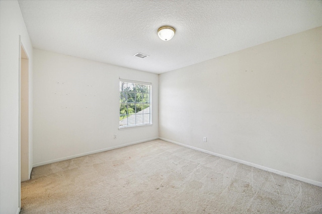 empty room featuring light colored carpet and a textured ceiling