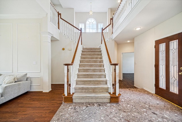 foyer entrance featuring crown molding, a towering ceiling, and dark hardwood / wood-style floors