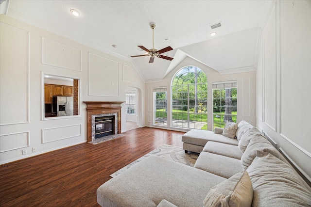 living room with ceiling fan, dark hardwood / wood-style flooring, a high end fireplace, crown molding, and vaulted ceiling