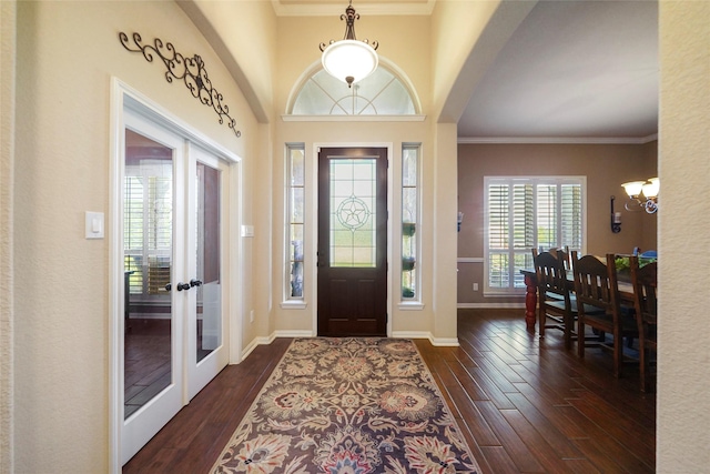 entryway with arched walkways, ornamental molding, and dark wood finished floors