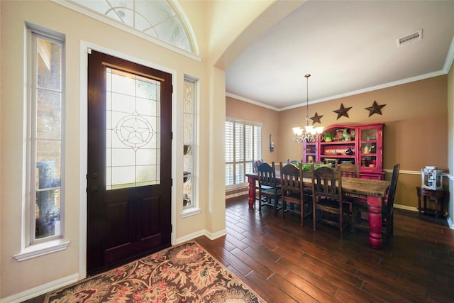 foyer entrance featuring baseboards, visible vents, dark wood finished floors, crown molding, and a notable chandelier