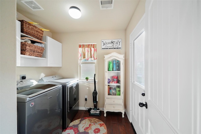 washroom featuring dark wood-type flooring, cabinet space, visible vents, and washing machine and clothes dryer