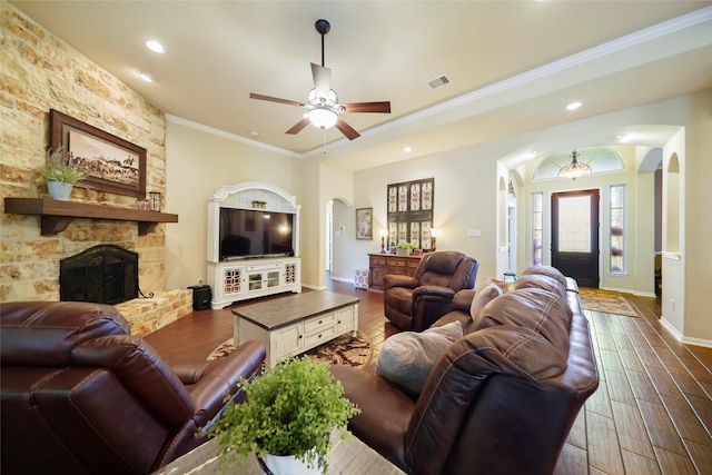 living room with visible vents, arched walkways, dark wood-style floors, crown molding, and a fireplace