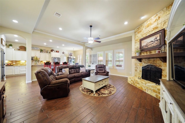 living room with ceiling fan, dark wood-style flooring, a fireplace, visible vents, and baseboards