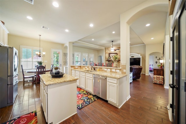 kitchen featuring visible vents, open floor plan, appliances with stainless steel finishes, a center island, and decorative light fixtures