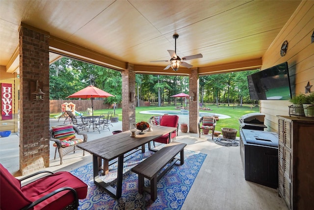 view of patio with outdoor dining area, fence, a pool, and a ceiling fan