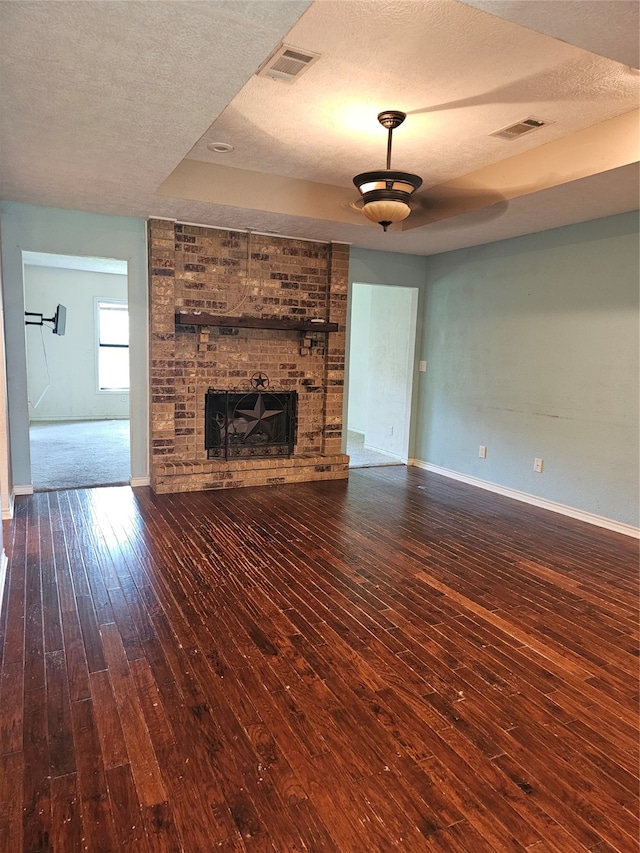 unfurnished living room featuring a fireplace, a textured ceiling, and dark hardwood / wood-style floors