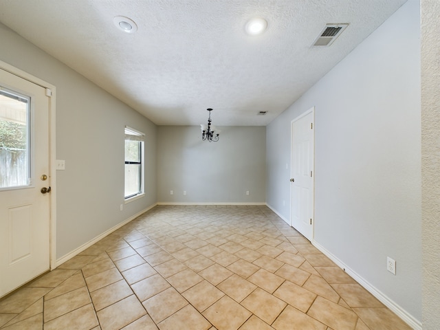 interior space with a notable chandelier, light tile patterned floors, and a textured ceiling