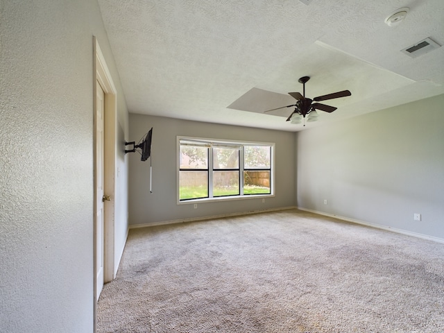 spare room with ceiling fan, light colored carpet, and a textured ceiling