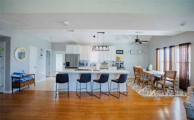 kitchen with white cabinetry, light hardwood / wood-style floors, stainless steel fridge, and plenty of natural light