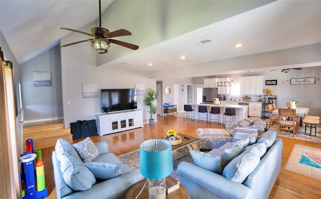 living room with high vaulted ceiling, sink, ceiling fan, and light wood-type flooring