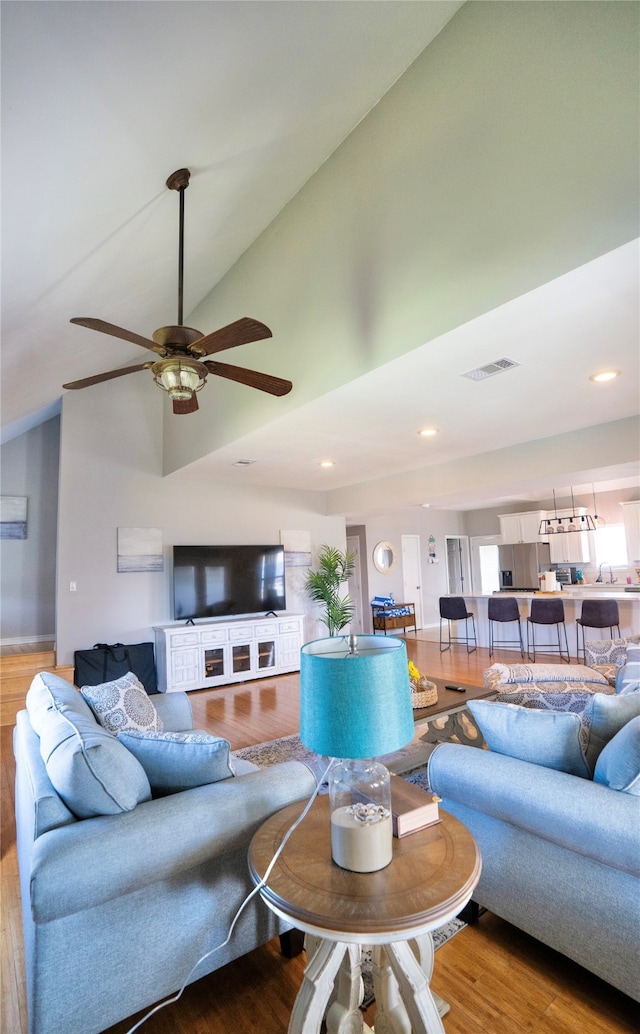 living room with high vaulted ceiling, ceiling fan, and light hardwood / wood-style floors