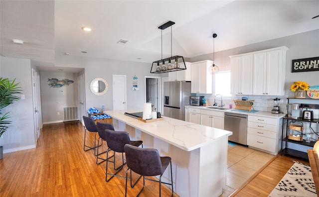 kitchen featuring stainless steel appliances, backsplash, light tile floors, sink, and white cabinets