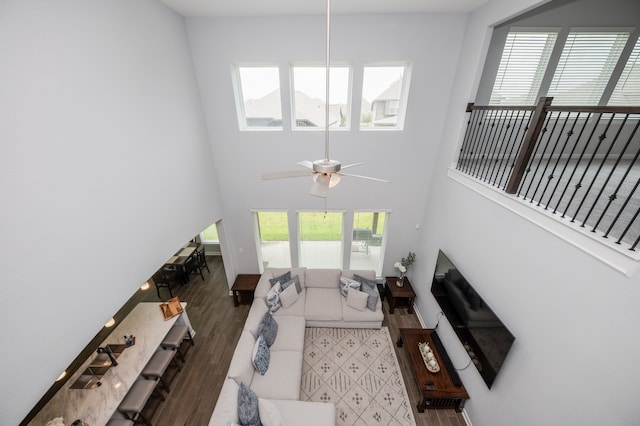 living room featuring ceiling fan, dark wood-type flooring, and a towering ceiling