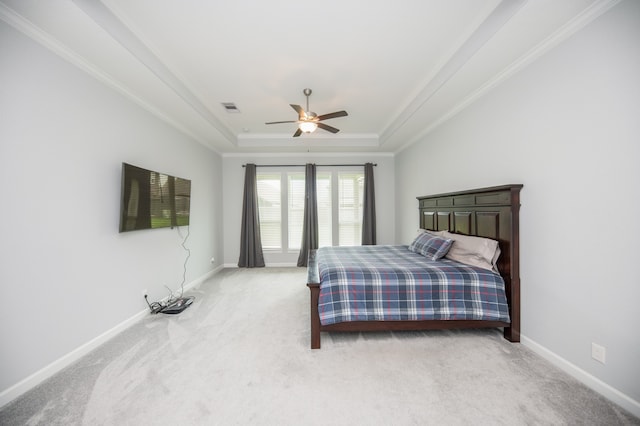 carpeted bedroom with ceiling fan, crown molding, and a tray ceiling