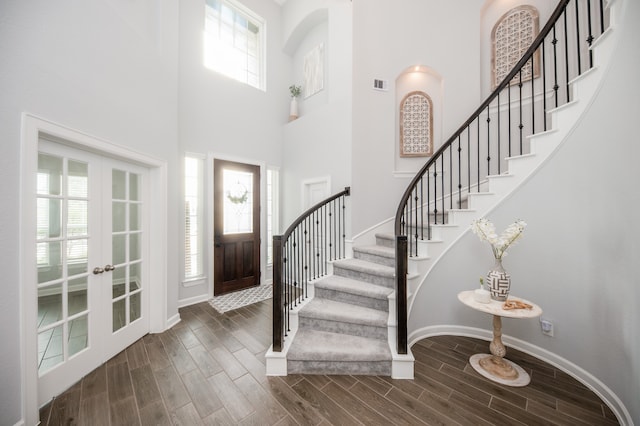 foyer entrance with a towering ceiling, french doors, and dark hardwood / wood-style floors