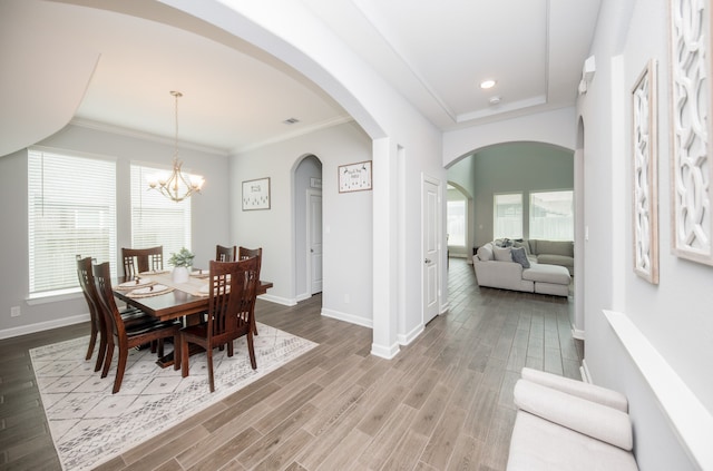 dining room featuring hardwood / wood-style floors, crown molding, an inviting chandelier, and a healthy amount of sunlight