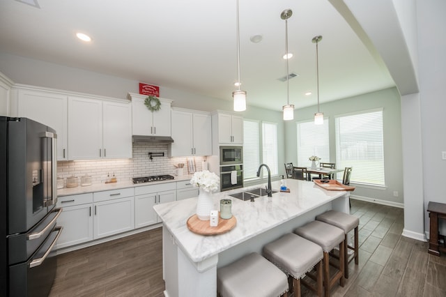 kitchen with white cabinets, decorative light fixtures, backsplash, stainless steel appliances, and sink