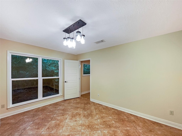 tiled empty room with a textured ceiling