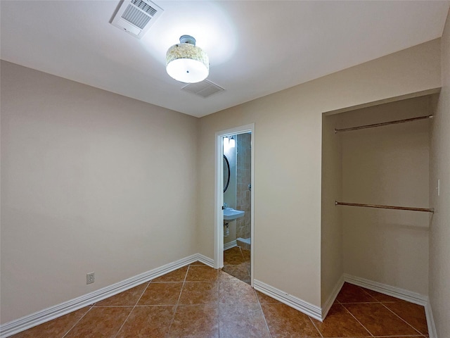 unfurnished bedroom with ensuite bathroom and dark tile patterned flooring