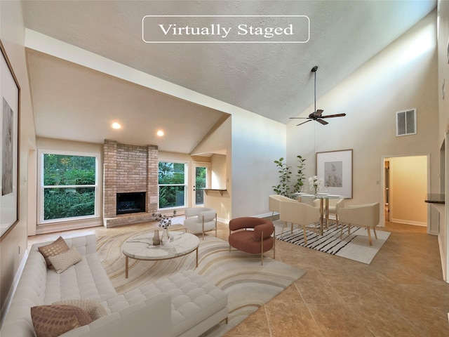 living room featuring visible vents, high vaulted ceiling, a ceiling fan, baseboards, and a brick fireplace