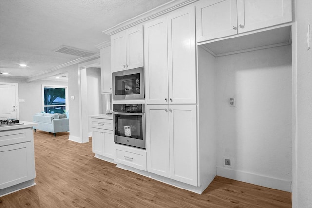 kitchen with light wood-type flooring, built in microwave, oven, and white cabinetry