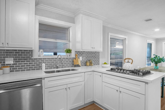 kitchen with tasteful backsplash, kitchen peninsula, sink, stainless steel appliances, and white cabinets