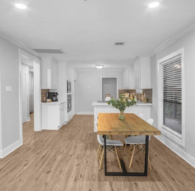 kitchen featuring decorative backsplash, light hardwood / wood-style floors, white cabinets, and stainless steel appliances