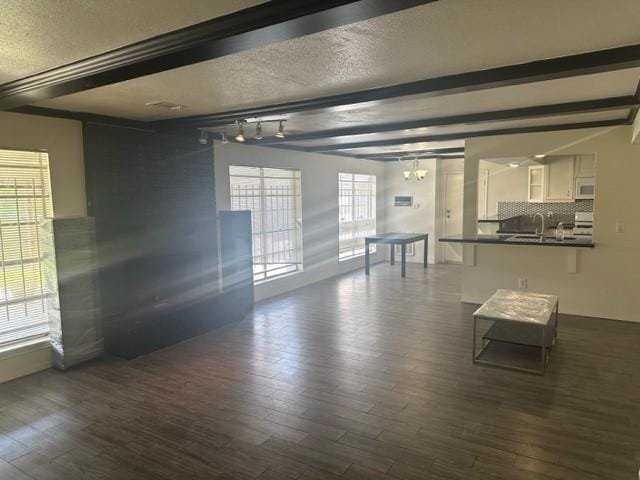 unfurnished living room featuring beamed ceiling and dark hardwood / wood-style floors