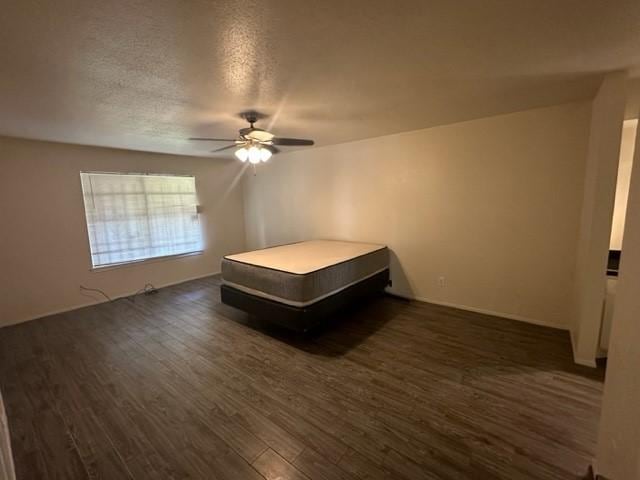 unfurnished bedroom featuring a textured ceiling, ceiling fan, and dark wood-type flooring