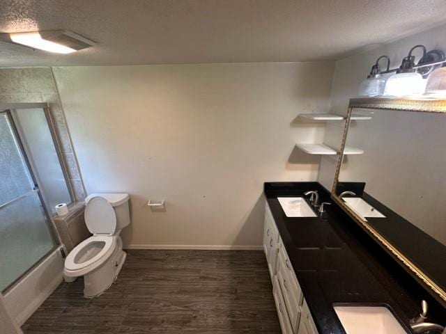 full bathroom with hardwood / wood-style floors, vanity, toilet, and bath / shower combo with glass door