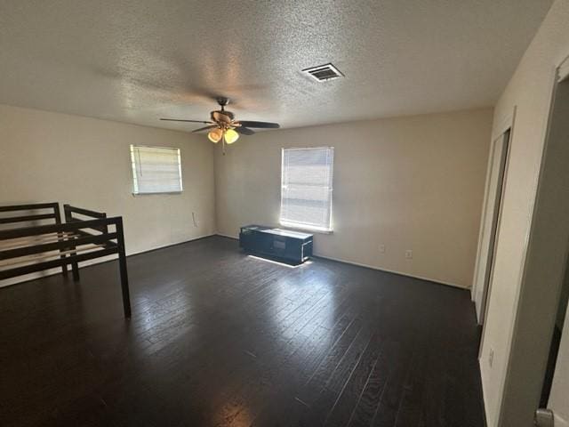 interior space featuring a textured ceiling, ceiling fan, and dark wood-type flooring