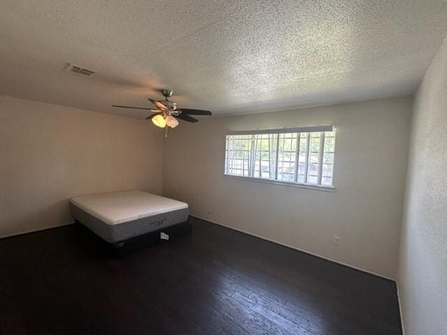 unfurnished bedroom with ceiling fan, dark hardwood / wood-style floors, and a textured ceiling