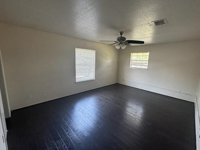 spare room with a textured ceiling, ceiling fan, and dark wood-type flooring