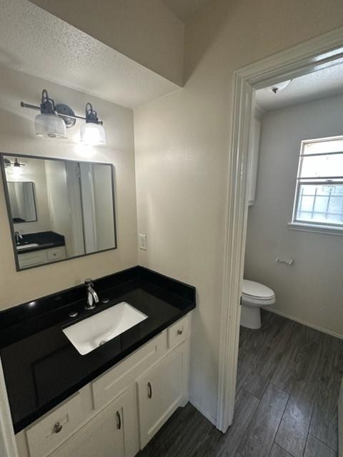 bathroom featuring vanity, hardwood / wood-style floors, a textured ceiling, and toilet