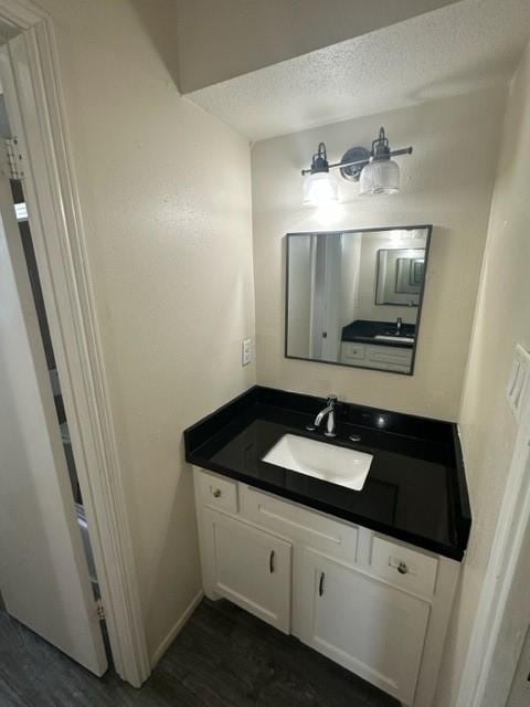 bathroom featuring hardwood / wood-style flooring, vanity, and a textured ceiling