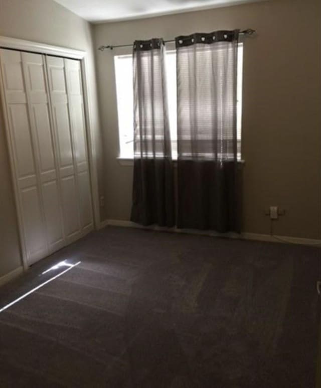 unfurnished bedroom featuring a closet and dark carpet