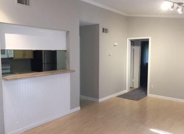 kitchen featuring black appliances, light hardwood / wood-style floors, ornamental molding, and kitchen peninsula