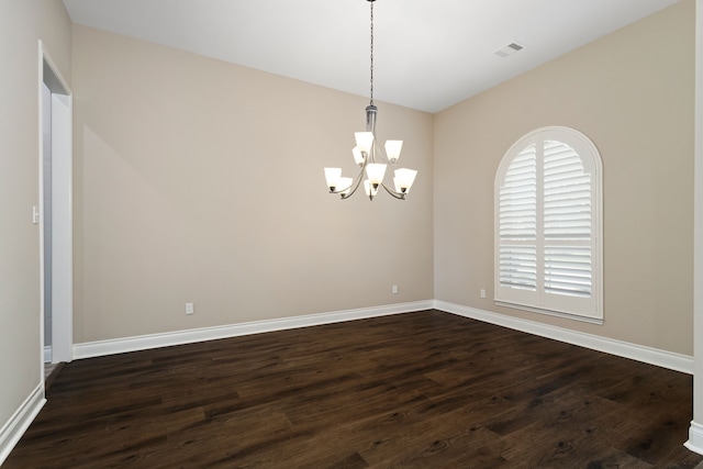 spare room with dark hardwood / wood-style floors and a notable chandelier