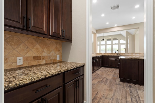 kitchen featuring tasteful backsplash, ceiling fan, sink, stone counters, and light hardwood / wood-style floors