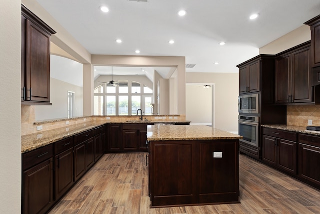 kitchen with sink, backsplash, kitchen peninsula, light hardwood / wood-style floors, and appliances with stainless steel finishes