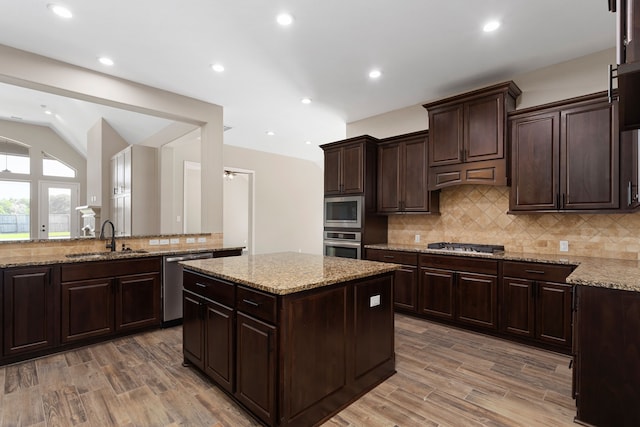 kitchen featuring wood-type flooring, appliances with stainless steel finishes, dark brown cabinetry, and sink