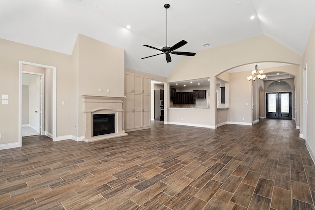 unfurnished living room with french doors, ceiling fan with notable chandelier, dark hardwood / wood-style floors, and high vaulted ceiling