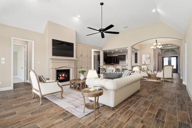 living room featuring high vaulted ceiling, dark wood-type flooring, and ceiling fan with notable chandelier